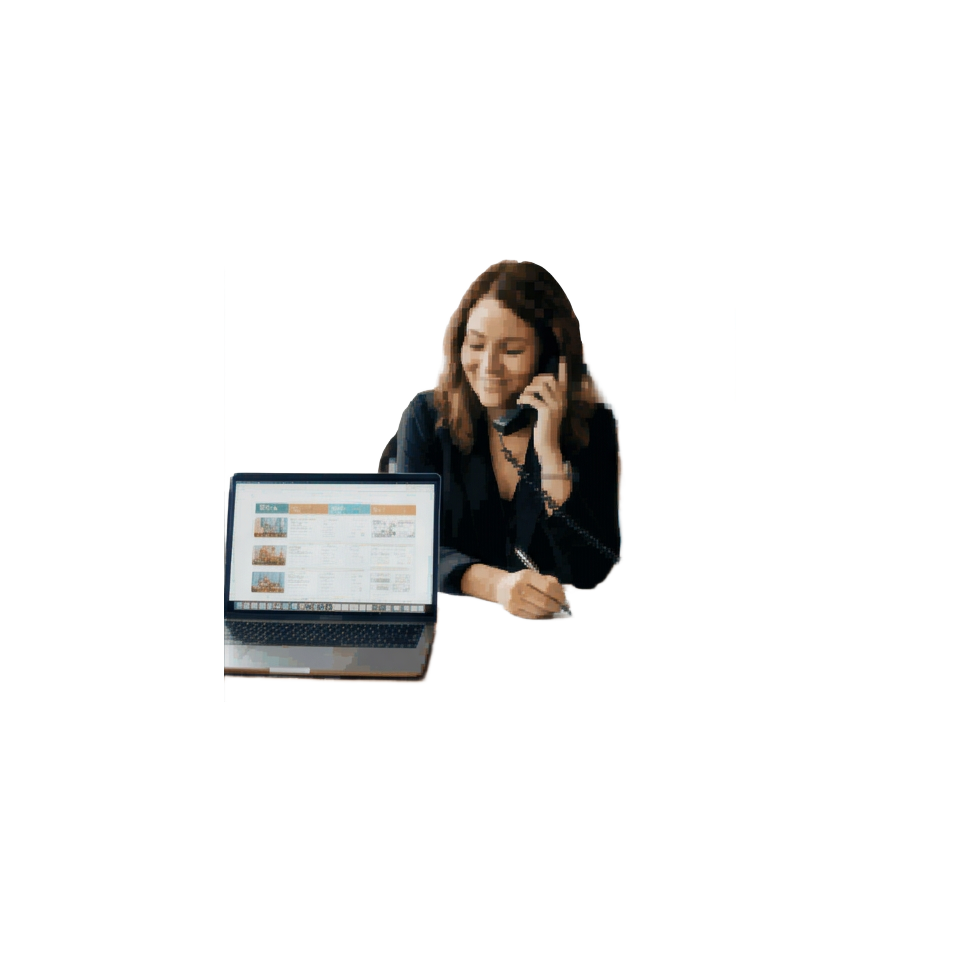 A travel advisor at a desk reviewing a draft itinerary on a laptop while talking with a client on the phone
